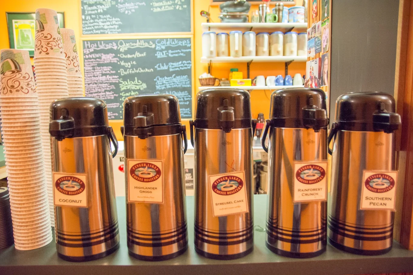 A row of coffee airpots labeled with the day's roasts