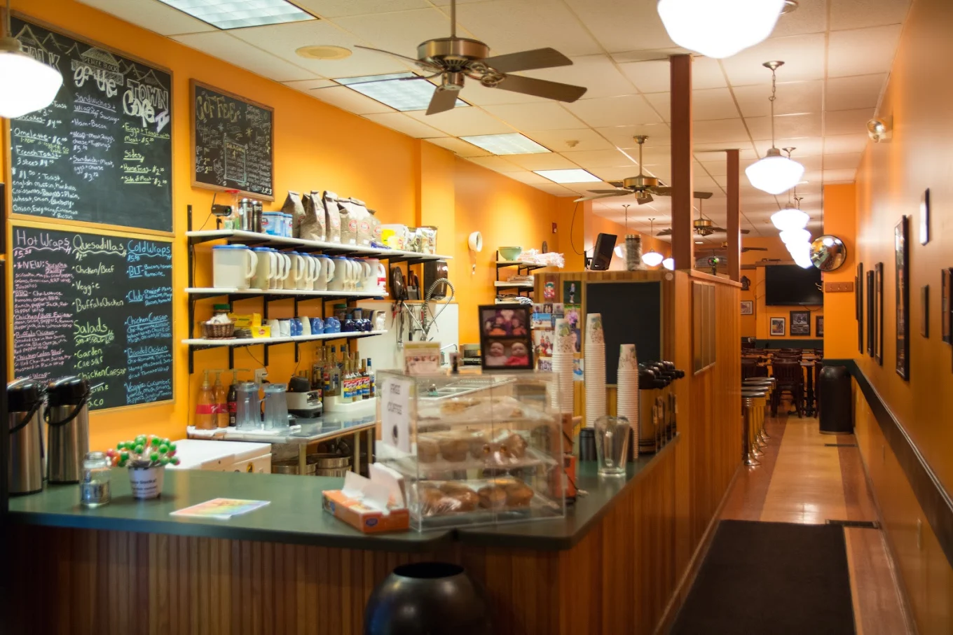 The cafe counter with chalkboard menus, a pastry case and coffee airpots