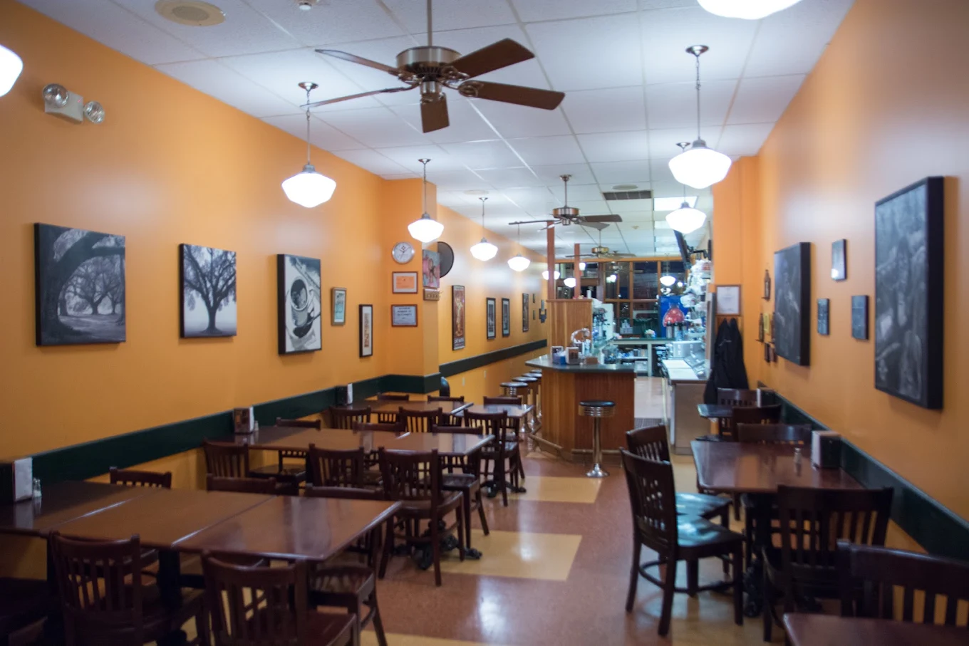The dining room: wooden tables and chairs along warm orange walls, with the counter at the back